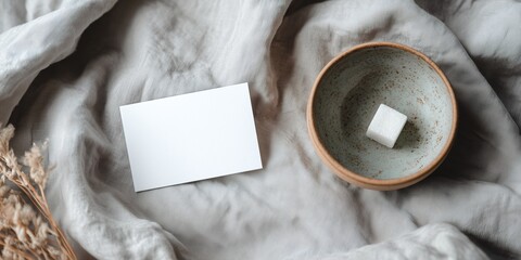 a blank postcard mockup and a simple ceramic sugar bowl on a light gray linen tablecloth