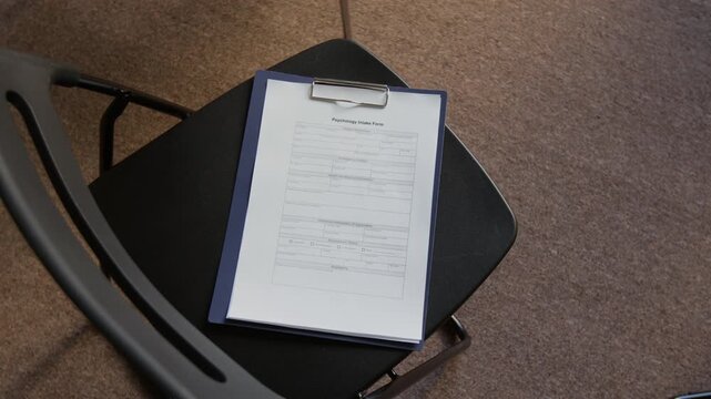Above shot of psychology intake form resting on chair in therapy room, document with empty sections prepared for clients information