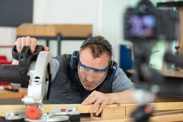 carpenter working on an electric buzz saw cutting some boards