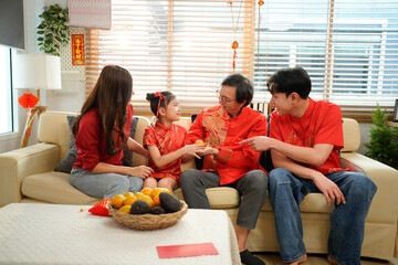 a multi-generational family exchanging red envelopes during their Chinese New Year celebration,...