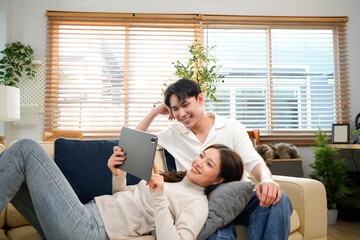 Laughing, tablet or happy couple on sofa to relax on social media for love or comfort on weekend in home. Mobile app, notification and people with smile on couch for funny joke