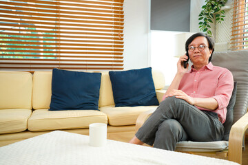Senior man talking on mobile phone at home. Laughing senior man talking on a cellphone while relaxing in a chair in his living room