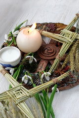Wiccan altar for Imbolc sabbat. witchcraft, magic ritual. wheel of the year with Brigid's cross, bowl with milk, candle, snowdrops flowers on table close up. symbol of Imbolc holiday, spring equinox