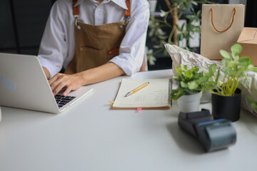 A small business owner, a florist or a retailer of plants working on a laptop managing orders for startup or an online business.&nbsp;