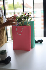 A florist working in retail shop, preparing order put in shopping bags for customer.