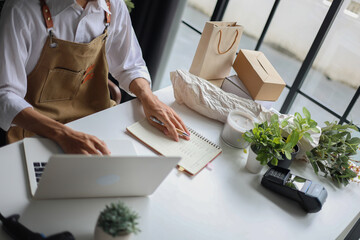 A small business owner, a florist or a retailer of plants working on a laptop managing orders for startup or an online business.&nbsp;
