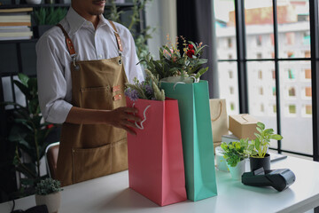 A florist working in retail shop, preparing order put in shopping bags for customer.
