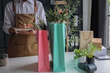 A florist working in retail shop, preparing order put in shopping bags for customer.