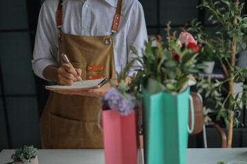 A florist working in retail shop, preparing order put in shopping bags for customer.
