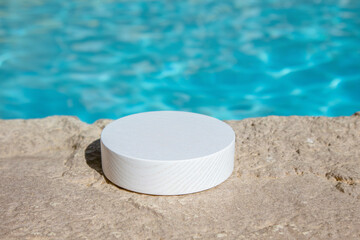 White wooden platform by a blue swimming pool with water, ideal as a product background. Lots of copy space, blurred background.