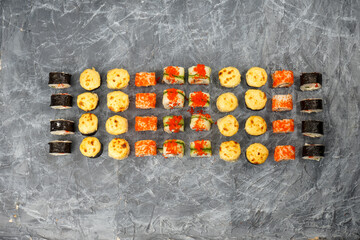 large sushi set with baked rolls and maki on a gray concrete background © polakravis