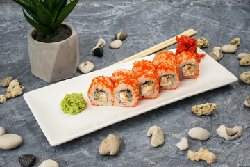 sushi rolls in caviar on a white plate on a gray background with food decor