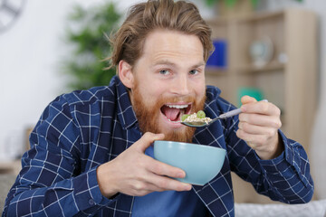 happy young man eating cereal with fruit