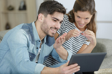 young couple at home using tablet to video chat