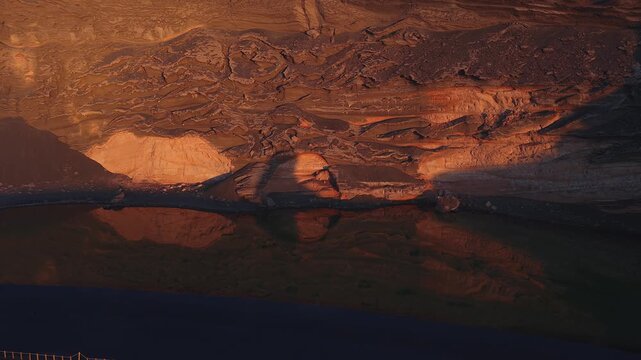 Layered volcanic cliffs, black sand, and a calm lagoon reflect at El Golfo, Lanzarote. Golden hour light sculpts lava bands as gentle ripples suggest slow movement.