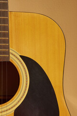 Obraz premium Close-up of acoustic guitar body and strings on a beige background with copy space