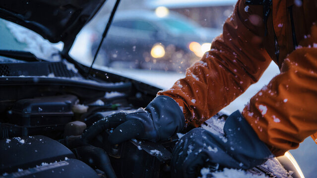 Car engine maintenance in winter, mechanic in warm clothing checks engine, cold weather vehicle troubleshooting, automotive repair outdoors, winter car care, snow-covered auto service - Powered by Adobe
