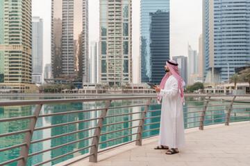 A real estate businessman in traditional Middle Eastern attire in a modern city with tablet