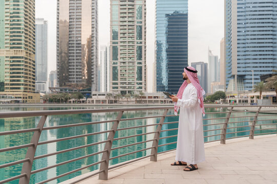 A real estate businessman in traditional Middle Eastern attire in a modern city with tablet