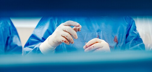 In a high-stakes surgical setting, gloved hands expertly handle instruments, showcasing dedication and precision amidst the challenges of the operating room, where every detail matters