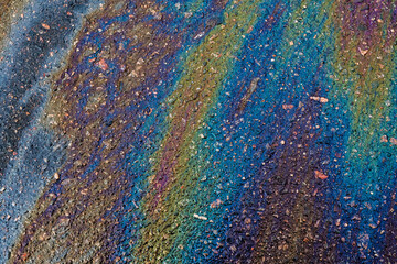 A vibrant oil slick on the road surface creates a visually appealing abstract background.