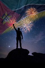 Man against background of a fireworks and national flag of Mozambique