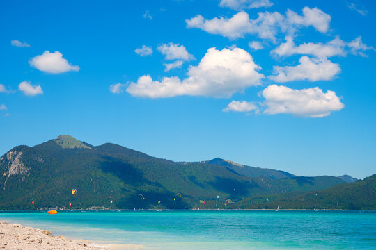 turquoise lake Walchensee with lots of kiters. Jochberg mountain at the left. blue sky with clouds