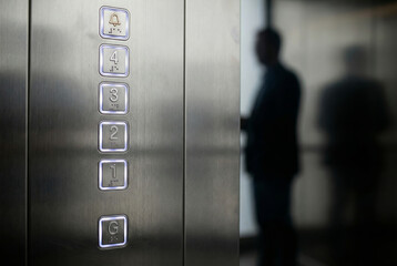 Stainless steel elevator control panel with illuminated floor buttons and braille accessibility features with person silhouette
