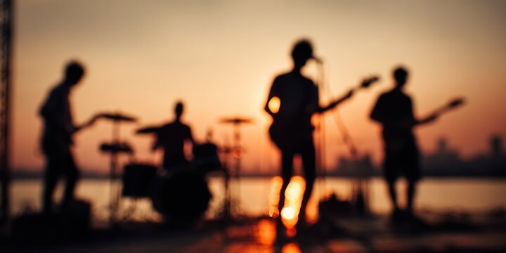 Silhouette of a band playing music at sunset on the beach.