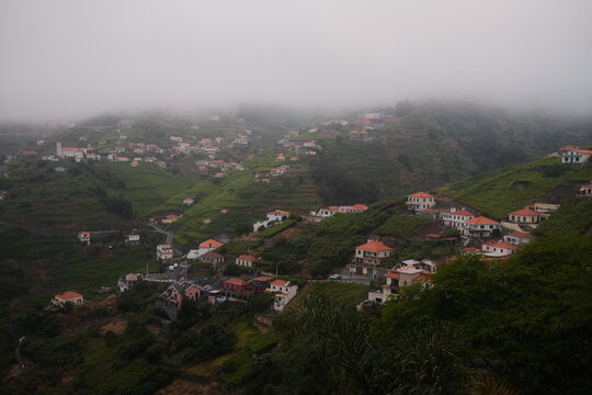 Misty Morning View Over Hillside Village with Red Roof Houses and Terraced Green Fields