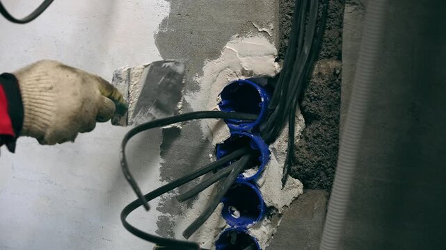 Industrial Renovation Scene Showing Expert Smoothing Of Wall Around Electrical Components With Safety Measures