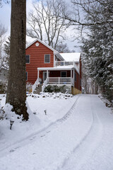 red suburban house with front yard and driveway covered with snow after snow storm