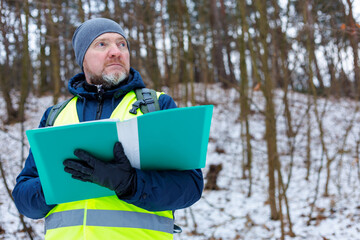Male biologist studies the condition forestry trees for a conservation report. Mature man ecologist in winter forest. Forester inspector.