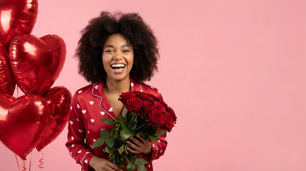 Joyful Black woman in heart pajamas holding bouquet of red roses with balloons