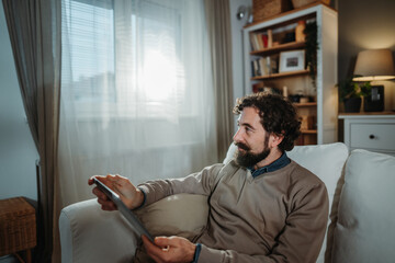 Man relaxing on sofa using tablet at home