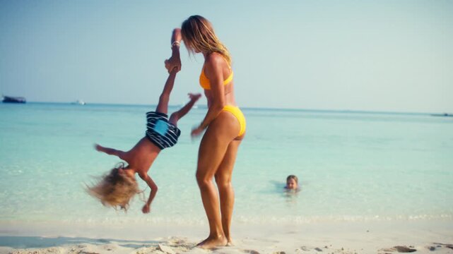A happy mother and her son enjoy playful moments on a beautiful tropical beach, creating cherished memories during their luxurious family vacation at an idyllic resort.