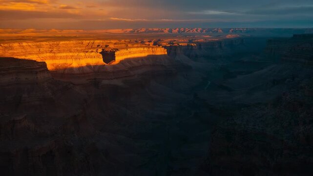 Glowing sunlit canyon rim catching low sun and revealing strata in deep canyon, with shadowed floor