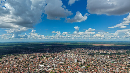 Aerial view of a sprawling city under a vast blue sky with fluffy white clouds