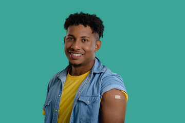 Smiling young man shows his arm after receiving a vaccine.