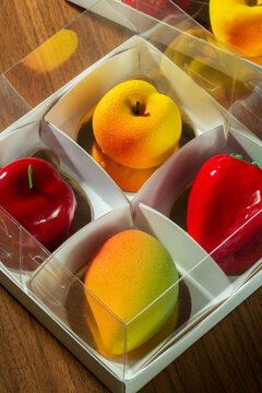 Gift set of mousse cakes in the shape of fruits and berries in a box.