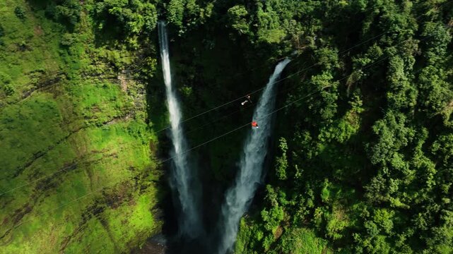 Aerial view of man ziplining over Tad Fane waterfall in tropical rainforest near Pakse and Champasak, Laos