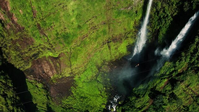 Aerial view of man ziplining over Tad Fane waterfall in tropical rainforest near Pakse and Champasak, Laos