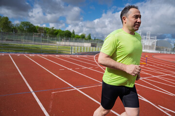Mature man running on stadium track outdoors