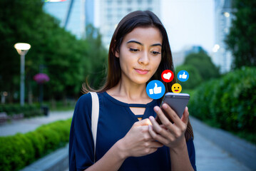 Young Woman Holding Smartphone with Social Media Icons, Walking Outdoors in City Park, Positive Engagement