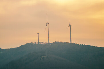 Wind turbines on a misty hill at sunset, generating clean energy for the future