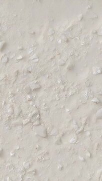 Vertical video: Drifting cam shifting focus filming wall closeup showing flakes specks for texture