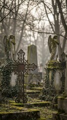 Fototapeta premium Old graveyard with ornate iron cross and weathered angel statues on a foggy day. Somber atmosphere for remembrance, grief, memorial, and funeral concept.