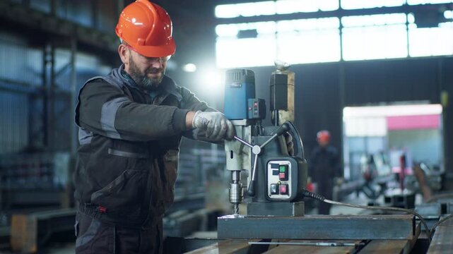 Professional blacksmith with safety helmet using heavy machine he make a hole in the metal at the repair workshop