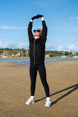 sporty woman doing arm stretching exercise at the beach