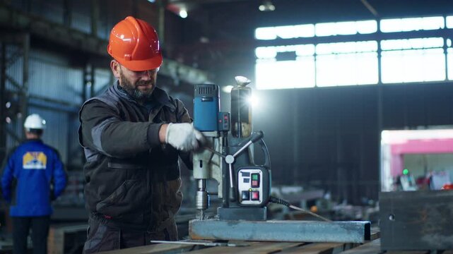 Blacksmith working in the industrial factory he make a hole in the metal he wearing safety equipment and glasses for protection